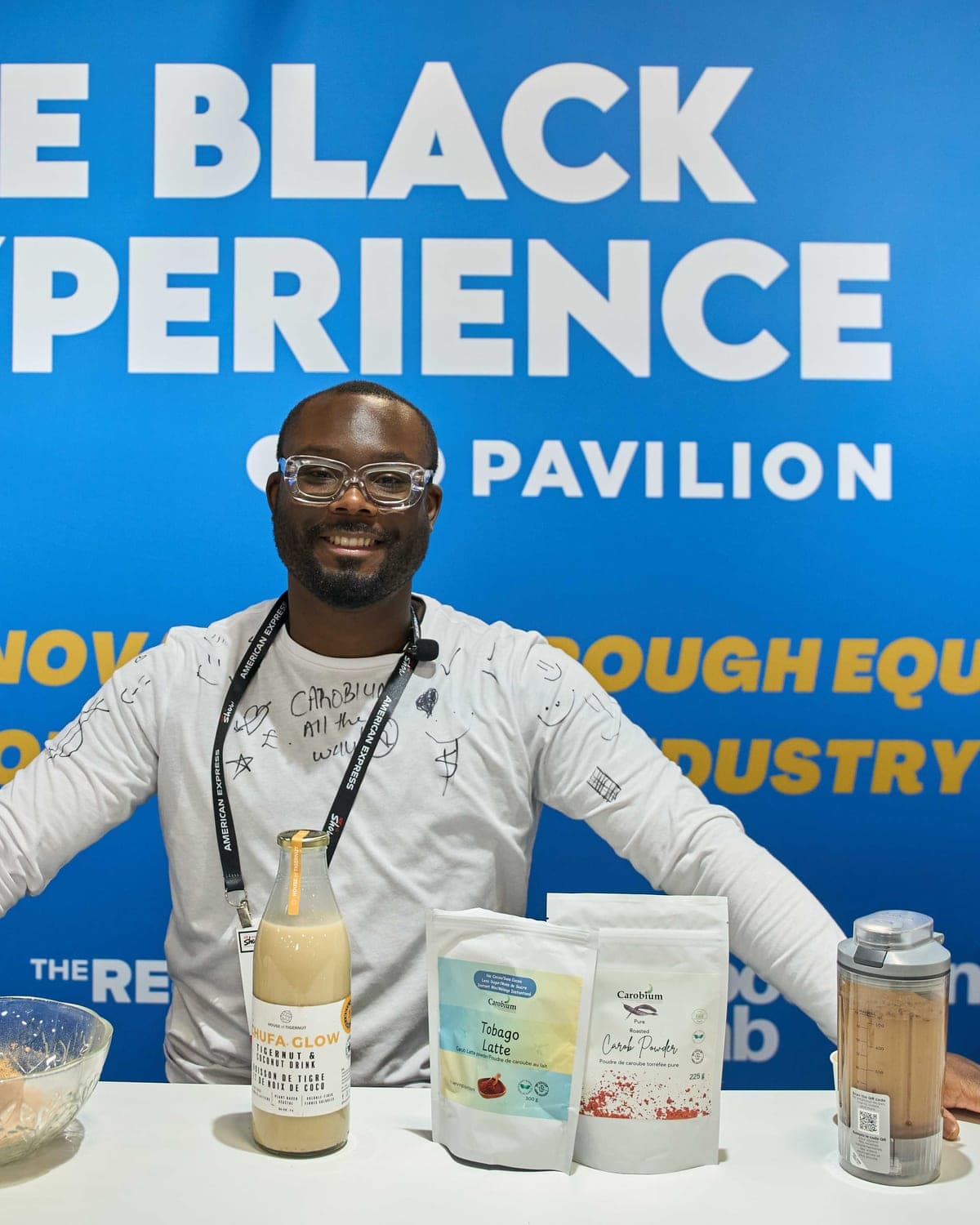 Kadeem George, founder of Carobium, behind a table set with Tobago Latte and Roasted Carob Powder
