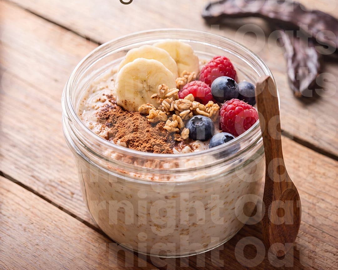 Jar of carob overnight oats topped with banana, berries and granola